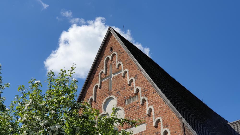 Kirkon pääty, jonka yläpuolella on sininen taivas ja pilvenhattara.