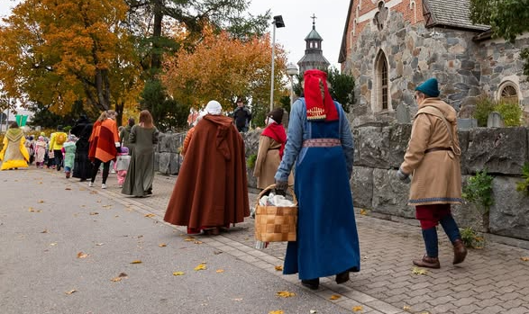 Keskiaikaisiin asuihin pukeutuneita aikuisia ja lapsia ohittavat Pyhän Birgitan kirkon kulkueena.