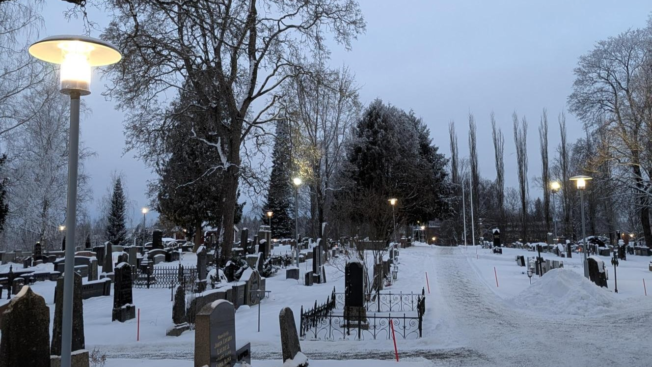 Hämärä hautausmaa, etualalla vasemmalla valopylväs.