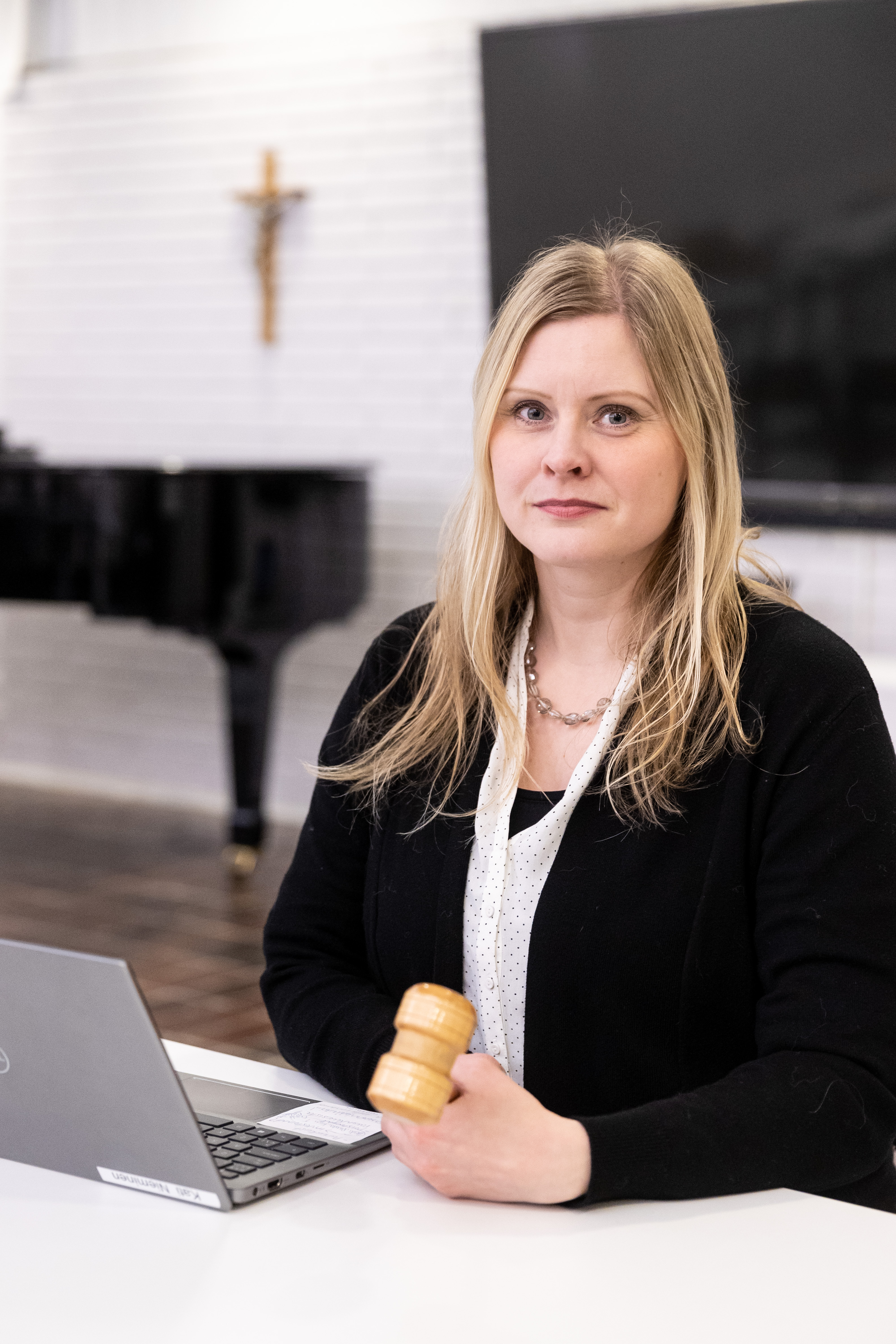Vaalea ja pitkähiuksinen kirkkovaltuuston puheenjohtaja Heidi Salonen istuu puheenjohtajan nuija kädessään.