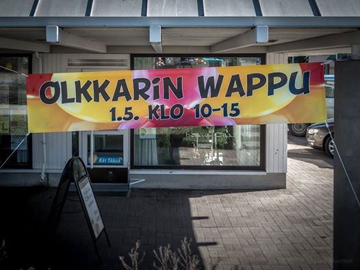 Iloinen, punakeltainen Olkkarin Wappu -mainoslakana kahvila Olkkarin edessä.