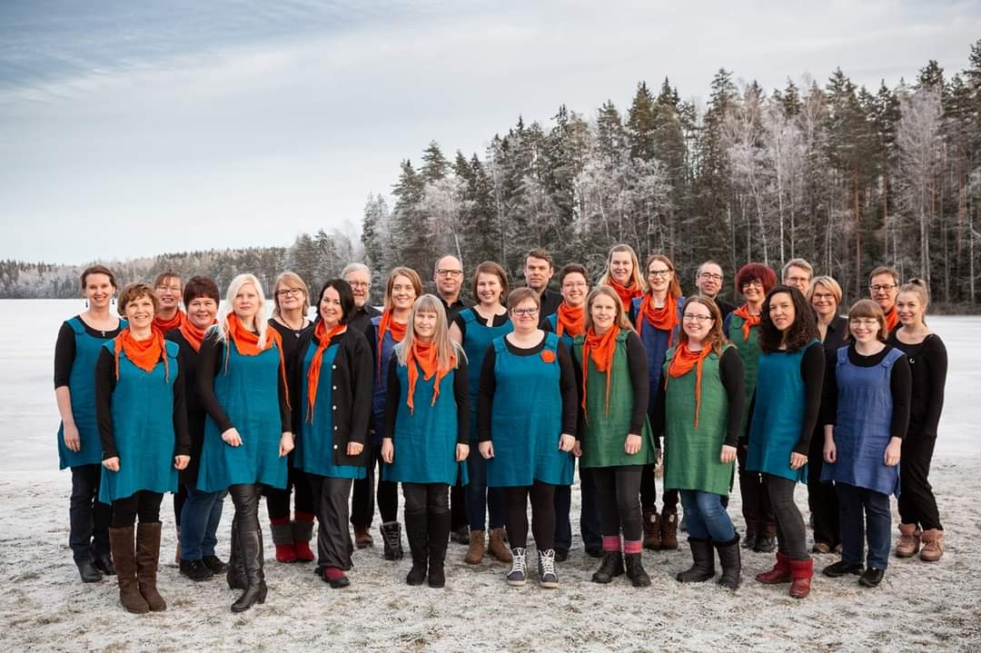 Pietari & Kalat -gospelkuoro värikkäissä esiintymisasuissa seisoo järven jäällä