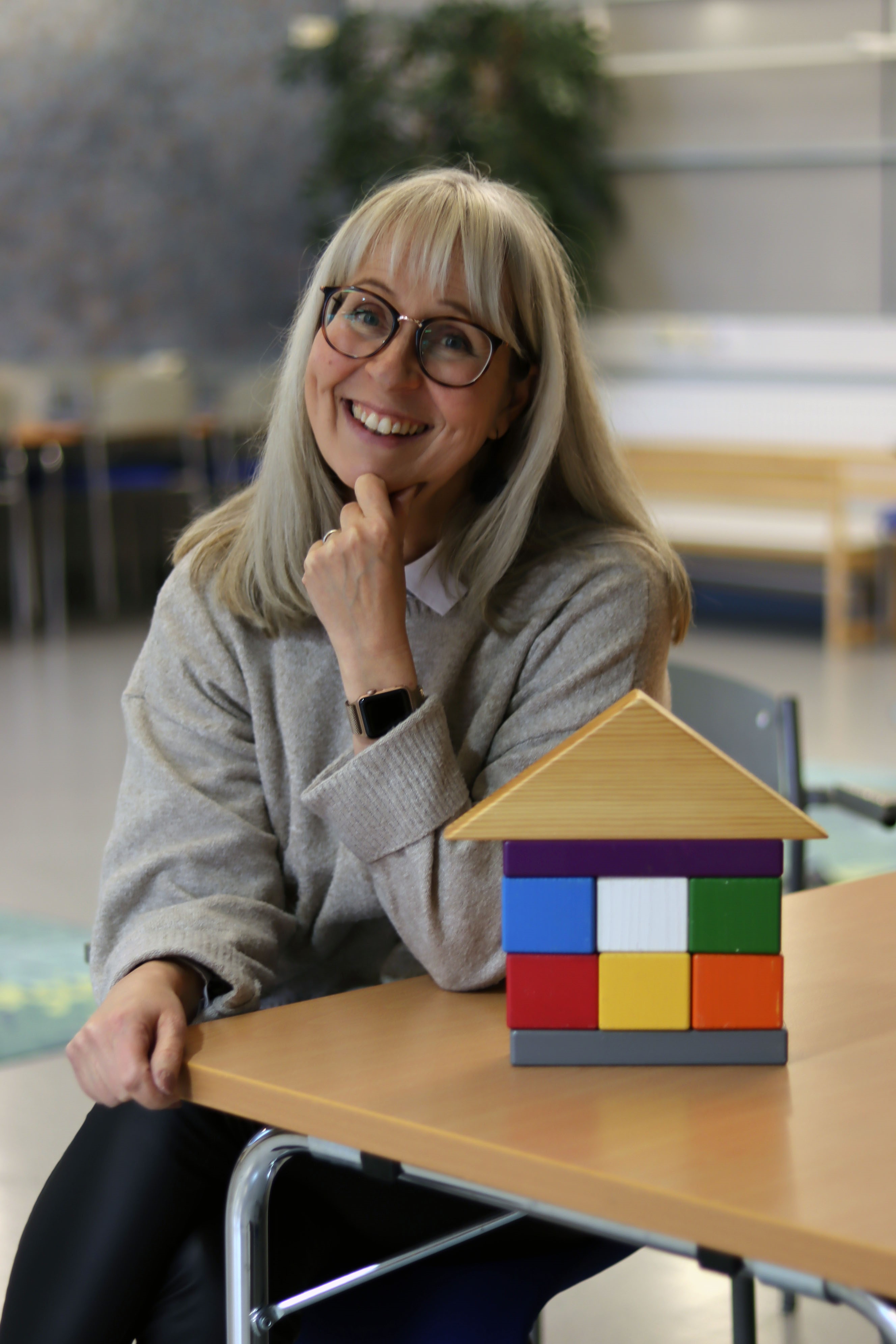 Vanhemmuuden palikkatalo eli erivärisiä puupalikoita talon  muodossa ja  perhetyönohjaaja Tiina Mäkinen