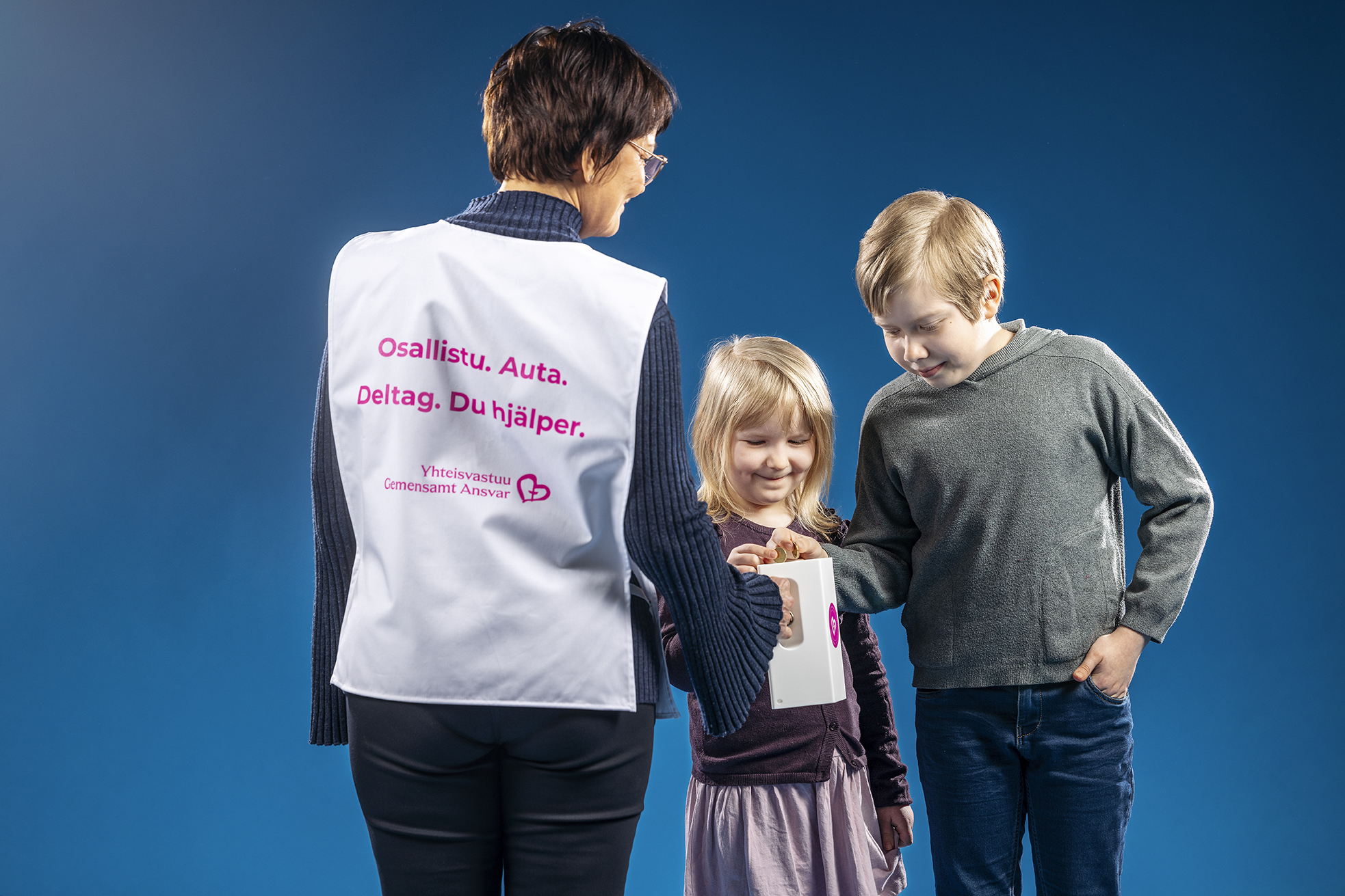 Yhteisvastuukeräyksen kampanjakuva, jossa kaksi lasta antaa rahaa lippaaseen.