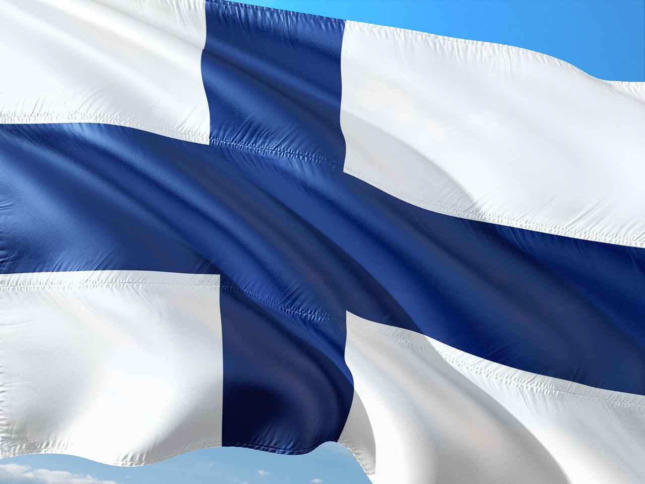 Suomen sinivalkoinen lippu liehuu taivaan sinessä.