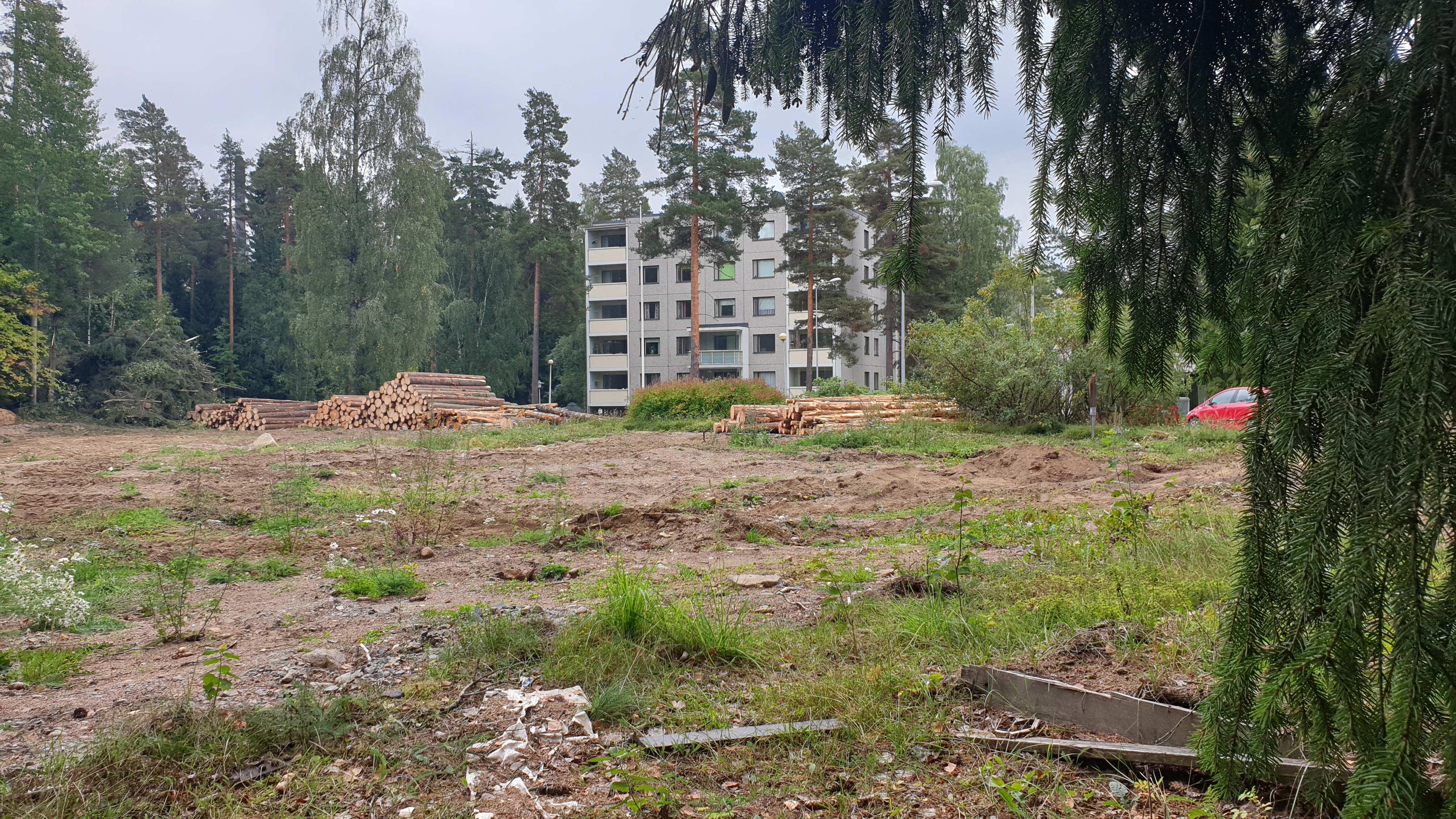 Rakentamaton tontti, jonka toisella reunalla on kerrostalo.