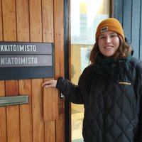 Keltapipoinen Liisa Nurminen avaa diakoniatoimiston oven. Ovessa on kyltti 