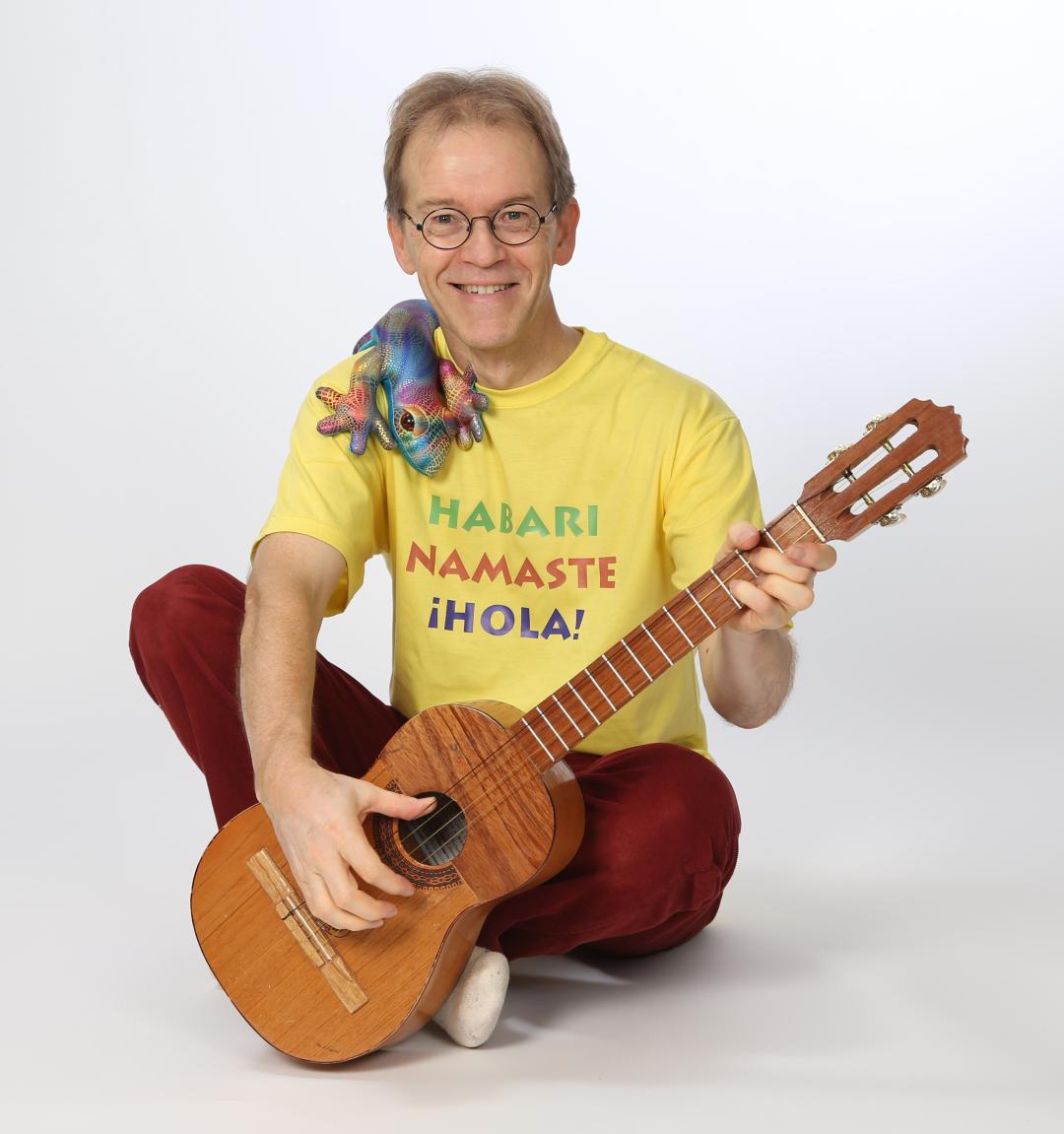 Jukka Salminen istuu maassa kitara sylissä ja pehmoeläin olkapäällä.  