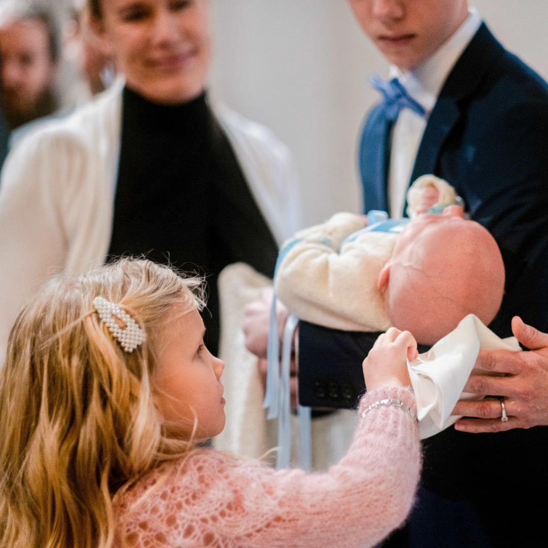kuva kasteesta: sisar kuivaa kastettavan vauvan pään 