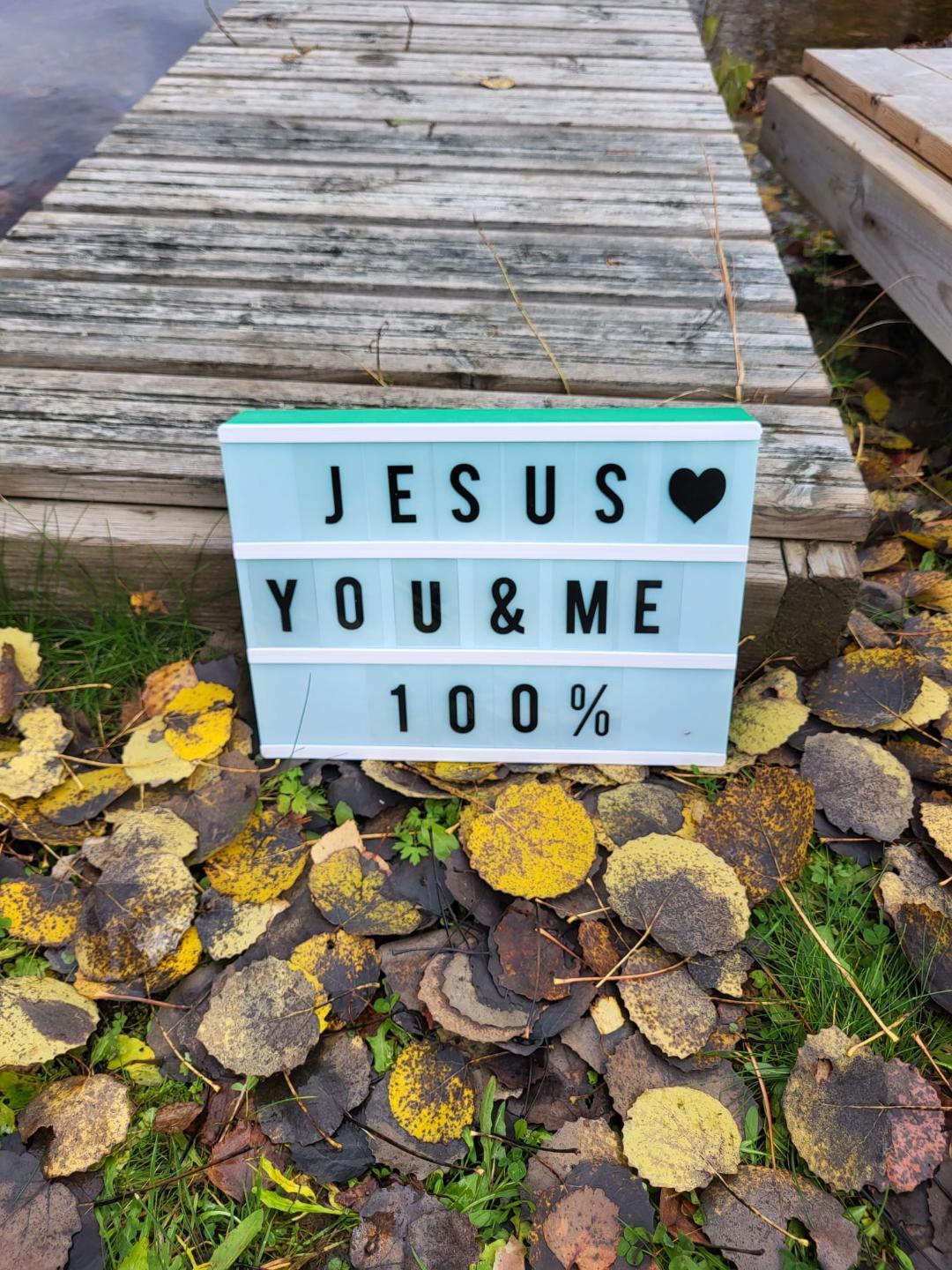 Kuvassa on syksyisen laiturin edessä kyltti jossa lukee Jeesus (sydän) You&Me 100%